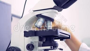 一名专业人员在<strong>使用显微镜</strong>时转动<strong>显微镜</strong>的眼睛